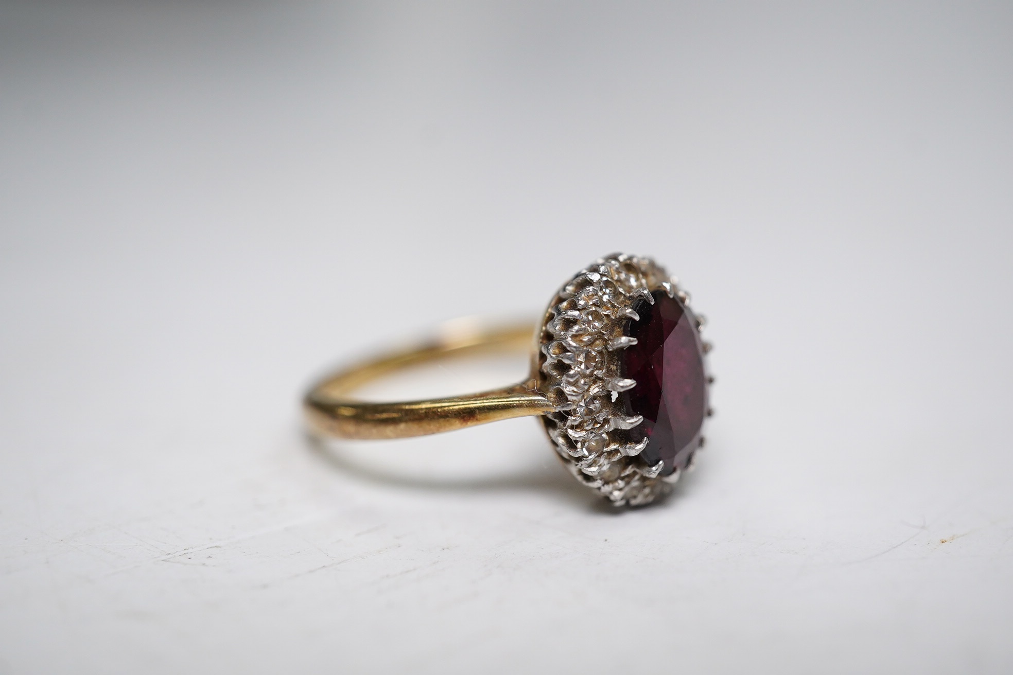 A 9ct and plat, garnet and diamond chip set oval cluster ring, size L, gross weight 3.9 grams. Condition - fair